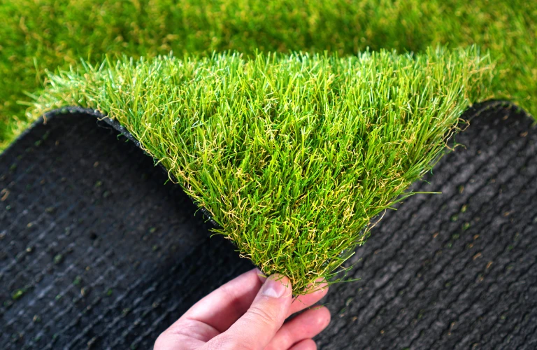 Hand holding an artificial grass roll Greenering with an artificial turf